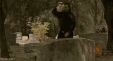 a man is standing in front of a gravestone with the name mcgowen written on it .