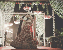 a bride and groom are dancing in front of a floral archway