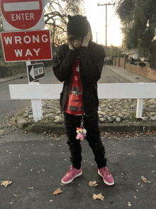 a person standing in front of a red sign that says wrong way