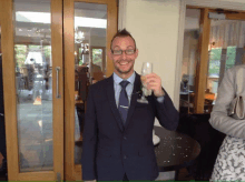 a man in a suit and tie holds a glass of wine