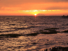 a sunset over a body of water with a dock in the distance