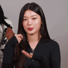 a woman wearing a black jacket is holding her hair
