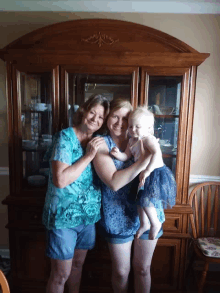 two women holding a baby in front of a display case