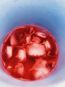 red ice cubes in a blue cup with water drops