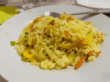 a white plate topped with rice and vegetables with a silver spoon