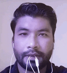 a man with a beard is wearing ear buds in his mouth