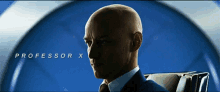 a bald man in a suit and tie is sitting in front of a blue background with the name professor x on it