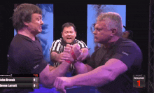 two men arm wrestling in front of a screen that says round one