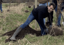 a man wearing rubber boots is kneeling down in the dirt