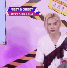 a young man is sitting in front of a sign that says meet & greet stray kids x tell .