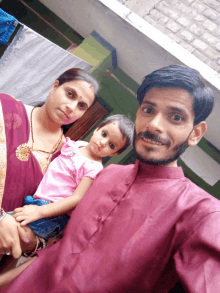 a man in a purple shirt poses with a woman and a child