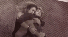 a man and a woman are hugging each other while laying on a carpet .