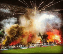 fireworks are going off in a stadium with a banner that says green