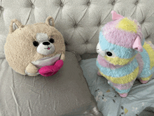 two stuffed animals are sitting on a bed including a dog and a llama