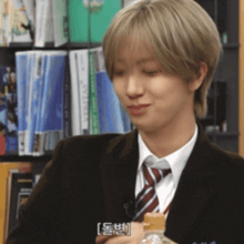 a man in a suit and tie is holding a bottle of water in front of a bookshelf