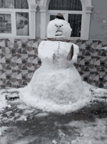 a snowman is standing in front of a building .