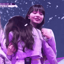 a girl in a purple outfit is hugging another girl in a purple outfit .