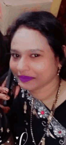 a woman with purple lipstick is holding a cell phone .