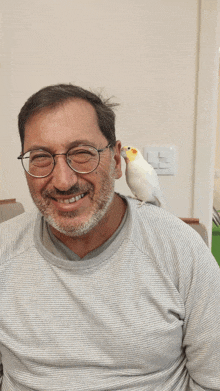 a man with glasses and a bird on his neck