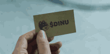 a person is holding a card that says $ dinu on it