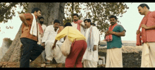 a group of men are standing around a tree talking to each other