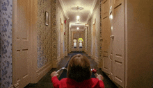 a girl in a red jacket sits in a hallway