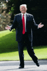 a man in a suit with a red tie is walking with his arms outstretched