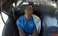 a man in a blue shirt is laying in a car with the date 2026-03-27