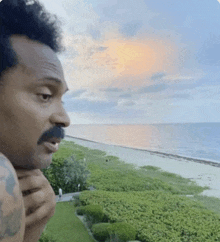 a man with a mustache is standing on a balcony overlooking the ocean .