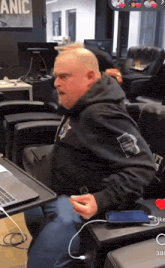 a man wearing a black hoodie with the word panic on it sits in front of a laptop