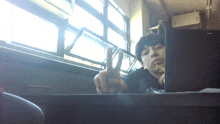 a man giving a peace sign while sitting at a desk