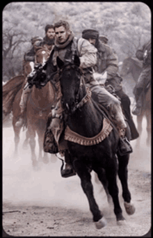 a group of men are riding horses in a dust storm