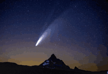 a mountain with a comet in the night sky