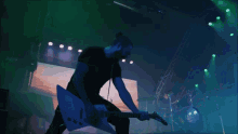 a man playing a guitar on a stage in front of a large screen