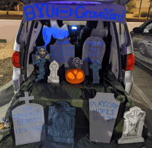 the trunk of a car is decorated for halloween with a sign that says byu graveyard