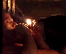 a man is lighting a cigarette with a lighter in a dark room