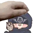 a person is holding a cat in their hand and a hand is putting something on top of their head .