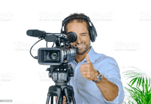 a man wearing headphones and a video camera is giving a thumbs up sign