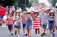 a group of children marching down a street with american flags