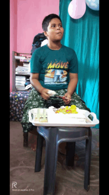 a young boy wearing a move shirt sits at a table with a cake