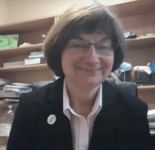 a woman wearing glasses and a button on her jacket