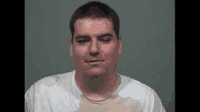 a man in a white shirt is looking at the camera in a mug shot .