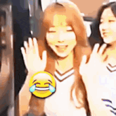 a woman is holding a yellow smiley face with tears coming out of her eyes and smiling .