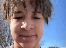 a close up of a young man 's face with curly hair making a funny face .