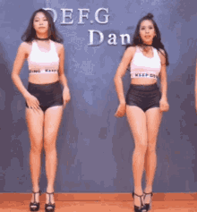 two young women are dancing in front of a sign that says efg dan