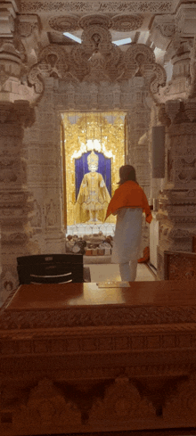 a man in an orange shirt stands in front of a statue