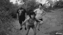 a black and white photo of a group of people standing next to each other on a dirt road .