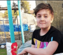 a young boy wearing a black shirt with a colorful design on it is smiling