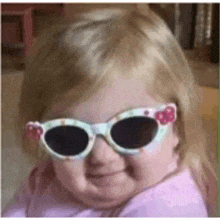 a little girl is wearing sunglasses and smiling .