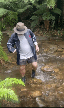 a man wearing a hat is walking through a stream